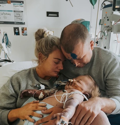 a man and woman are holding a baby in a hospital room