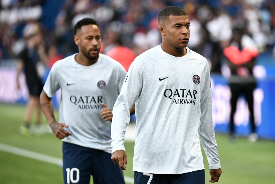 two soccer players wearing qatar airways jerseys walk on the field