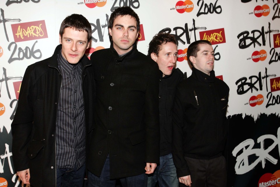 a group of men standing in front of a wall that says brit awards 2006