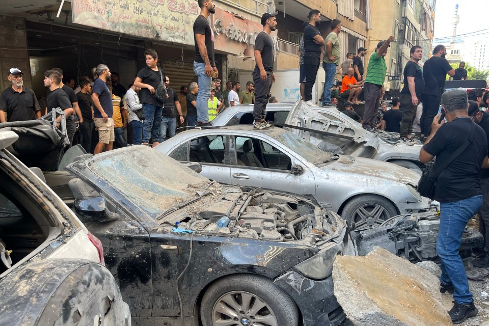 People stand on cars which were hit in the blast