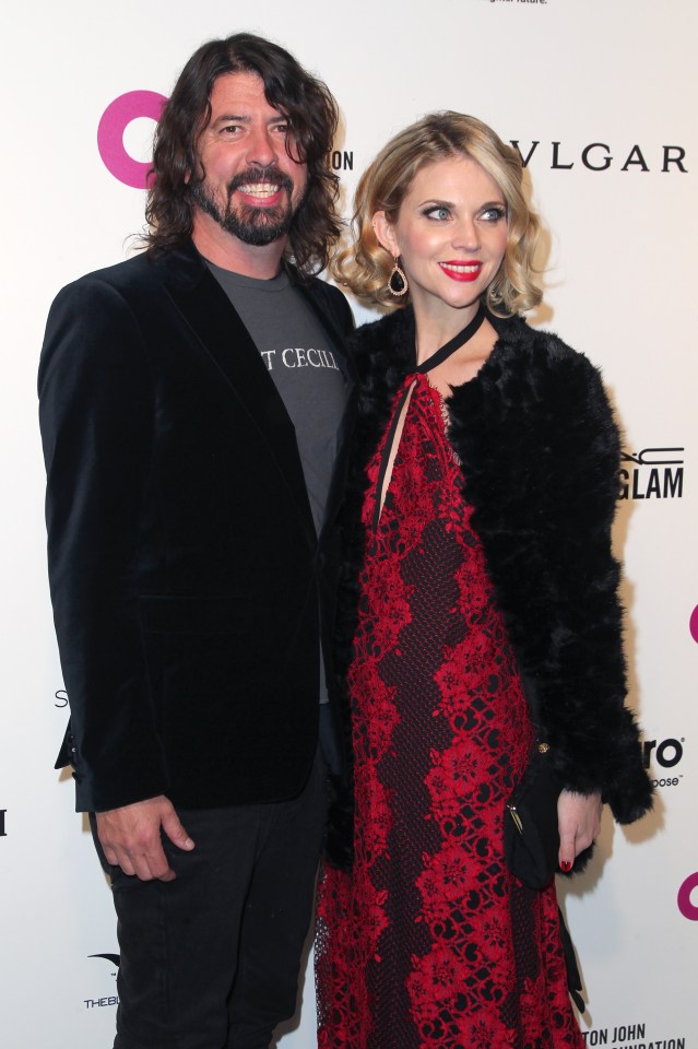 a man and woman pose on a red carpet in front of a bvlgari sign