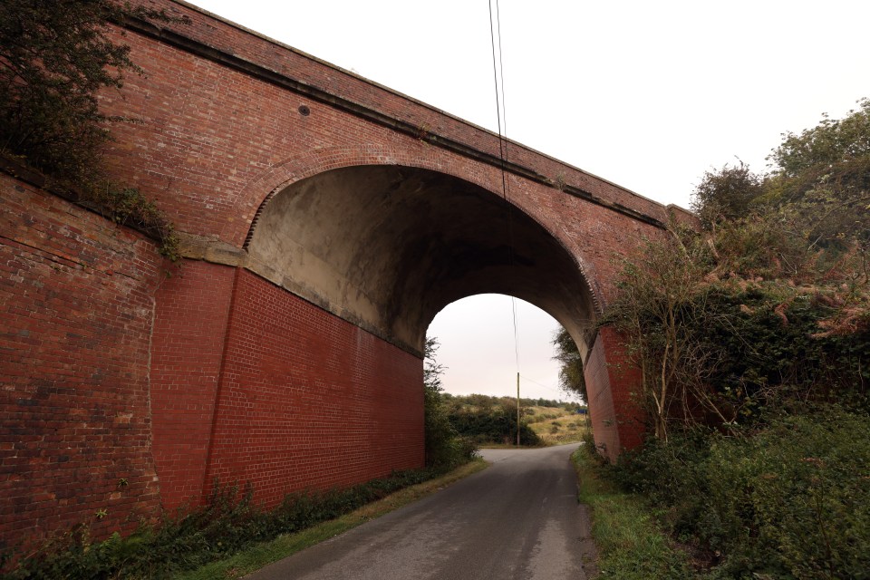 a brick bridge over a road with a white sky in the background