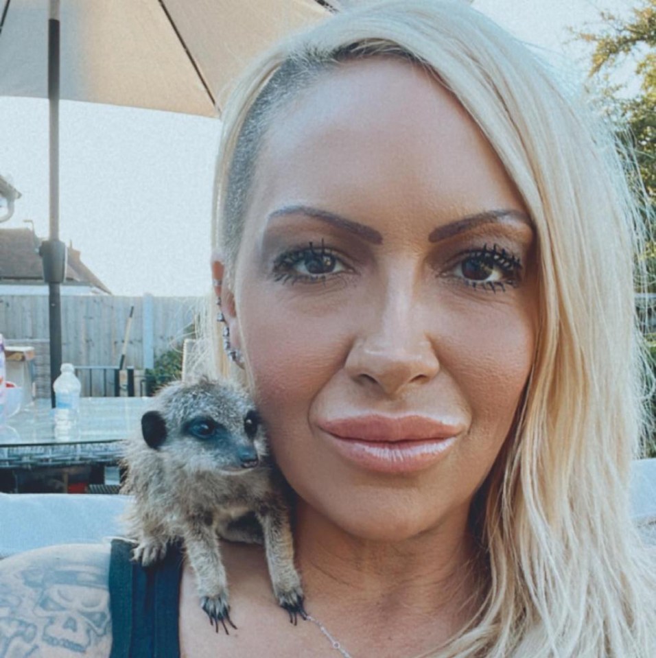 a blonde woman holds a small meerkat on her shoulder