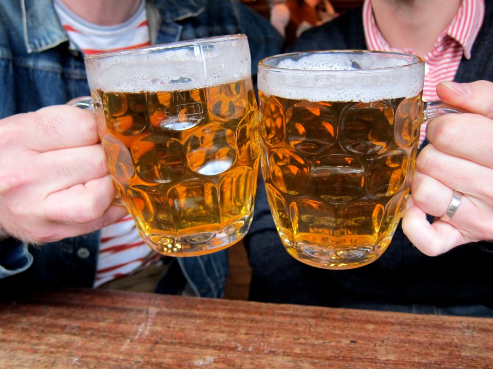 a man and a woman are toasting with two mugs of beer