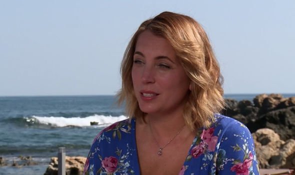 a woman in a blue floral dress is sitting on the beach looking at the ocean .