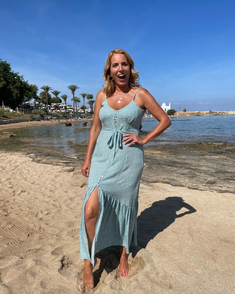 a woman in a green dress is standing on a sandy beach