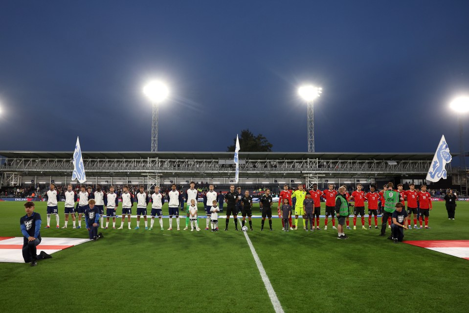 a group of soccer players stand on a field in front of a stadium