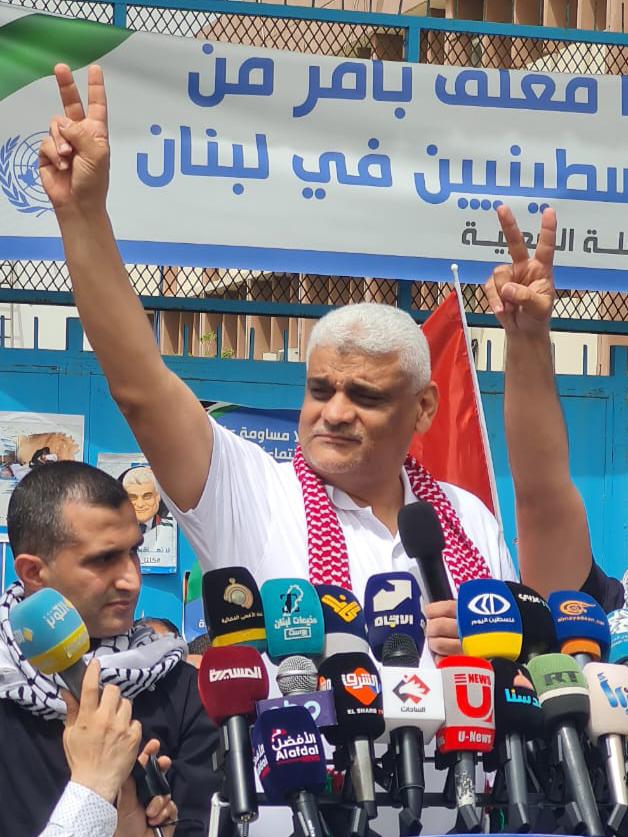 a man giving a peace sign in front of a sign that says ' u-nom ' on it