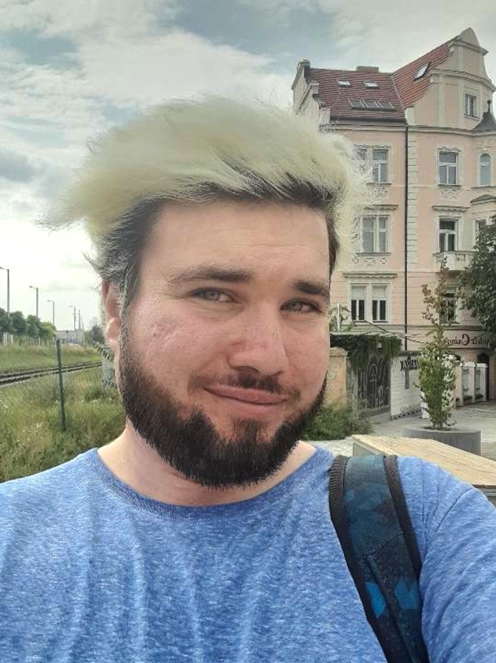 a man with a beard is wearing a blue shirt and a backpack