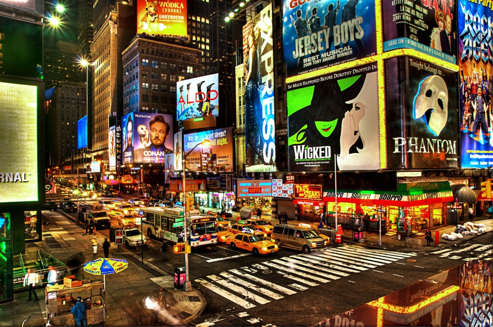 a busy city street with signs for wicked and phantom