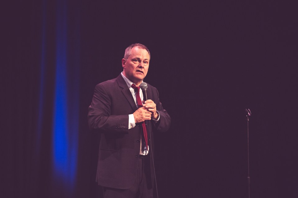 a man in a suit and tie is speaking into a microphone