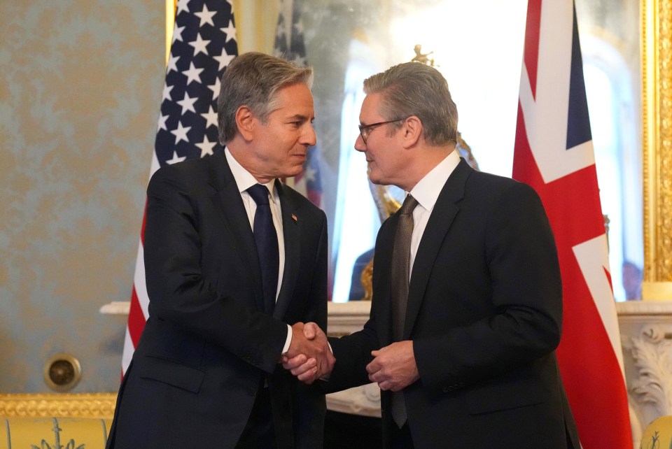 two men shaking hands in front of an american flag and a british flag