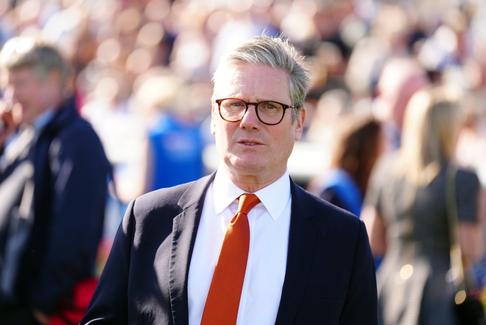 a man wearing glasses and an orange tie stands in a crowd