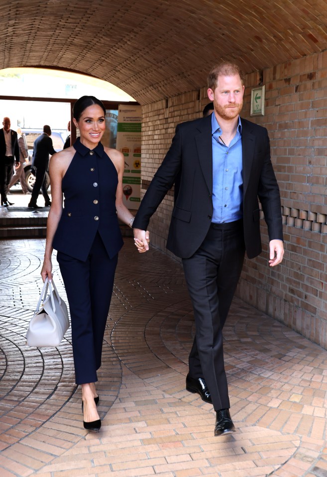 prince harry and meghan markle walk through a tunnel holding hands