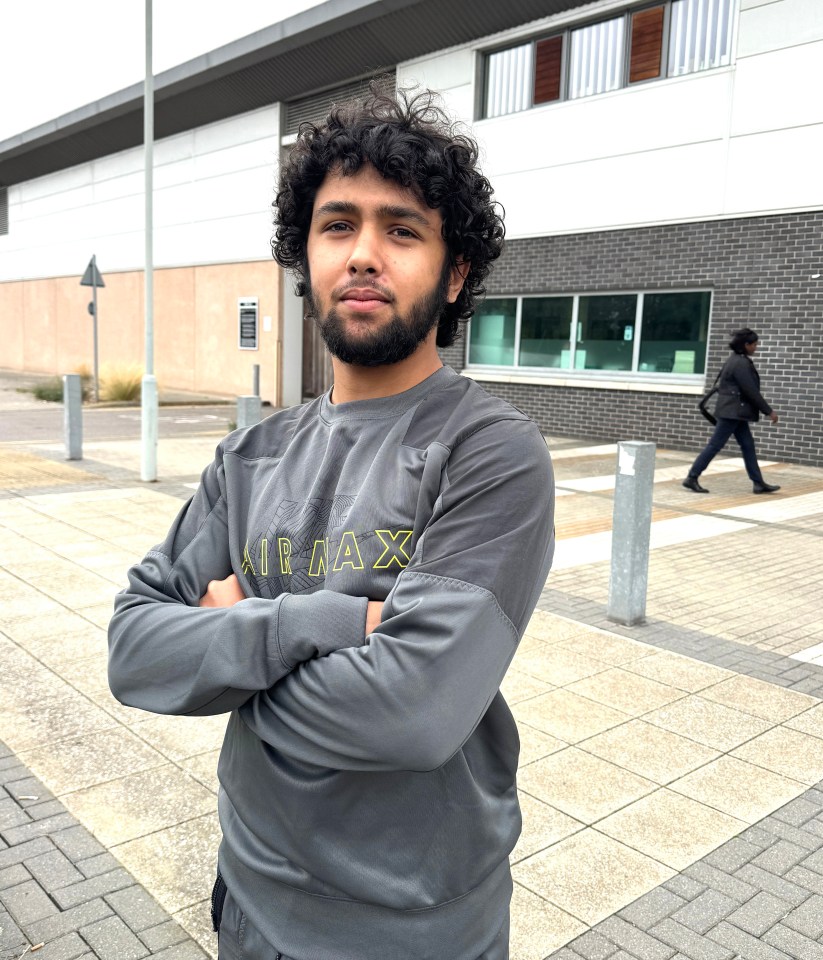 a man wearing a grey air max sweatshirt stands with his arms crossed