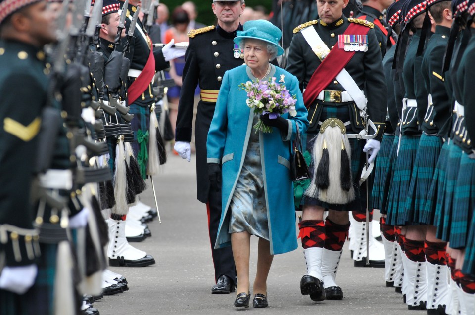 queen elizabeth walking in front of a marching band