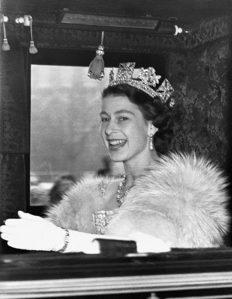 a woman wearing a fur coat and a tiara smiles for the camera