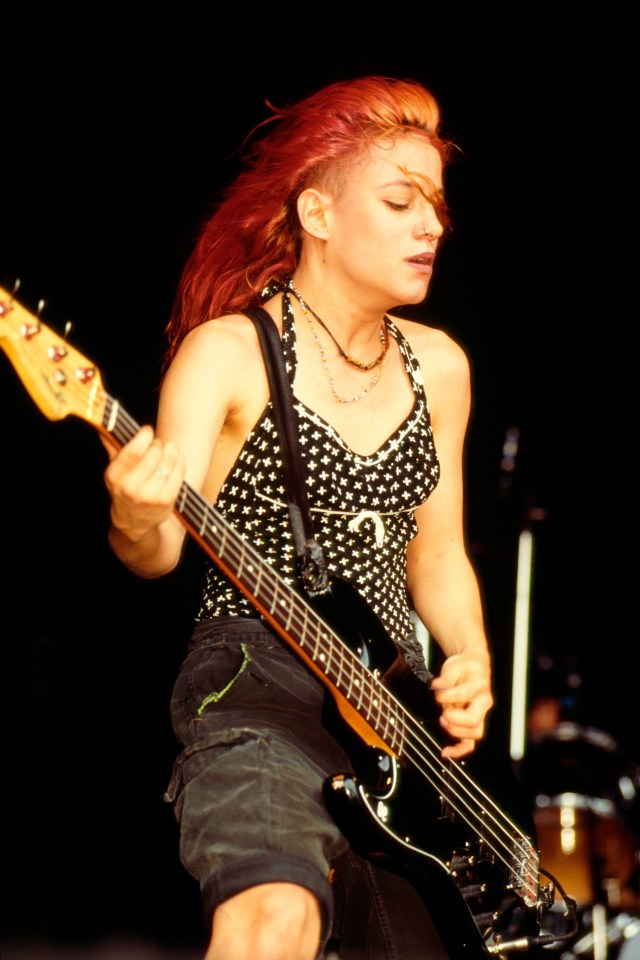 a woman with red hair is playing a bass guitar