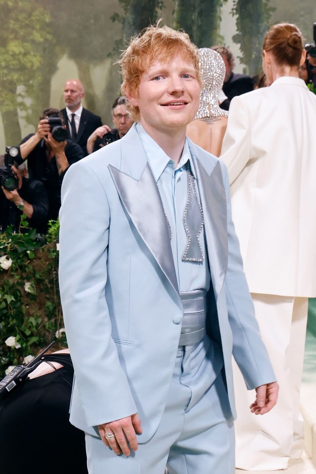 a man in a light blue suit smiles for the camera