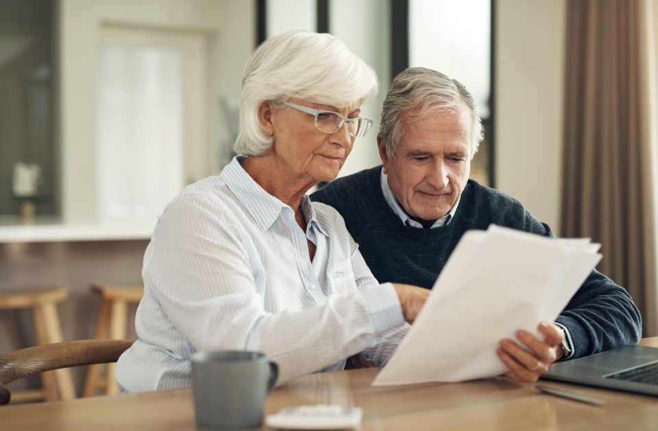 a man and woman sit at a table looking at a piece of paper