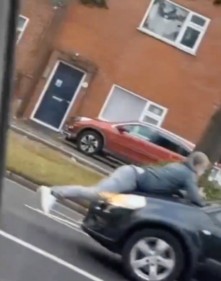 The man clings onto the bonnet of the car as the motorist drives off