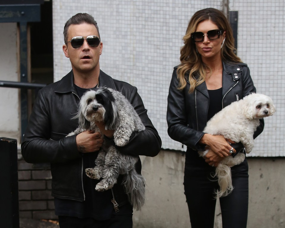 a man and a woman are holding two small dogs