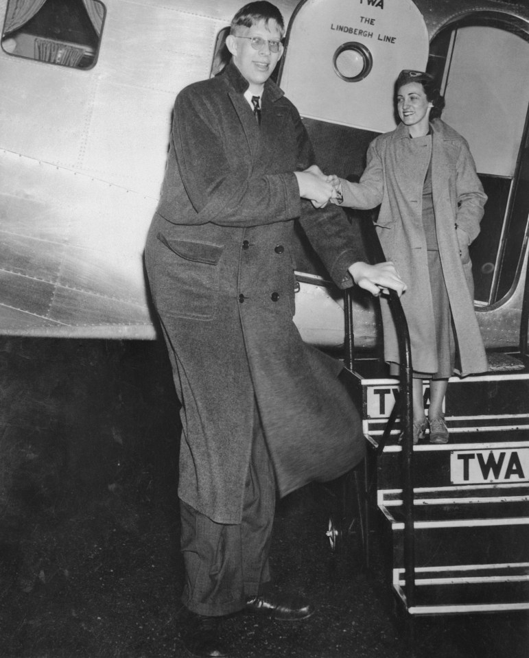 a man and woman shaking hands in front of a twa plane