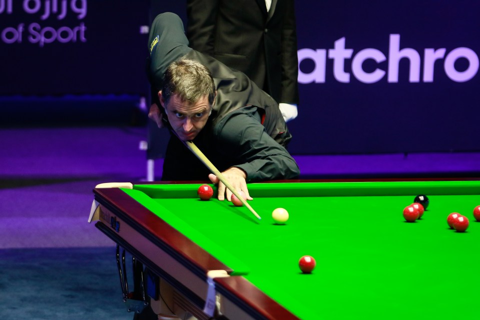 a man is playing pool in front of a sign that says atchro