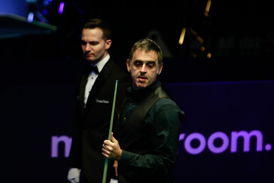 a man holding a cue in front of a sign that says room