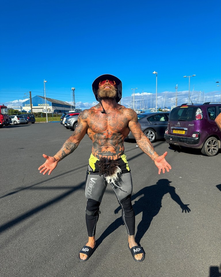 a man standing in a parking lot with his arms outstretched wearing mp sandals