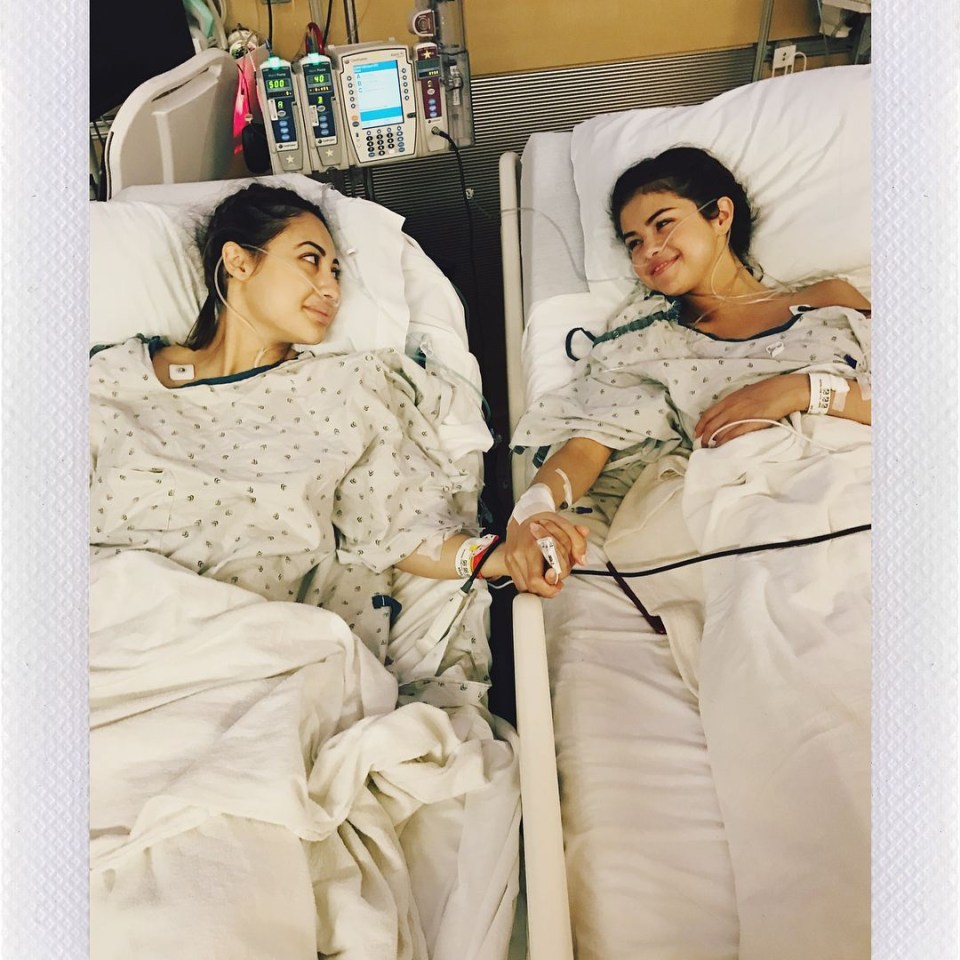 two women in hospital beds holding hands and one has a needle in her arm