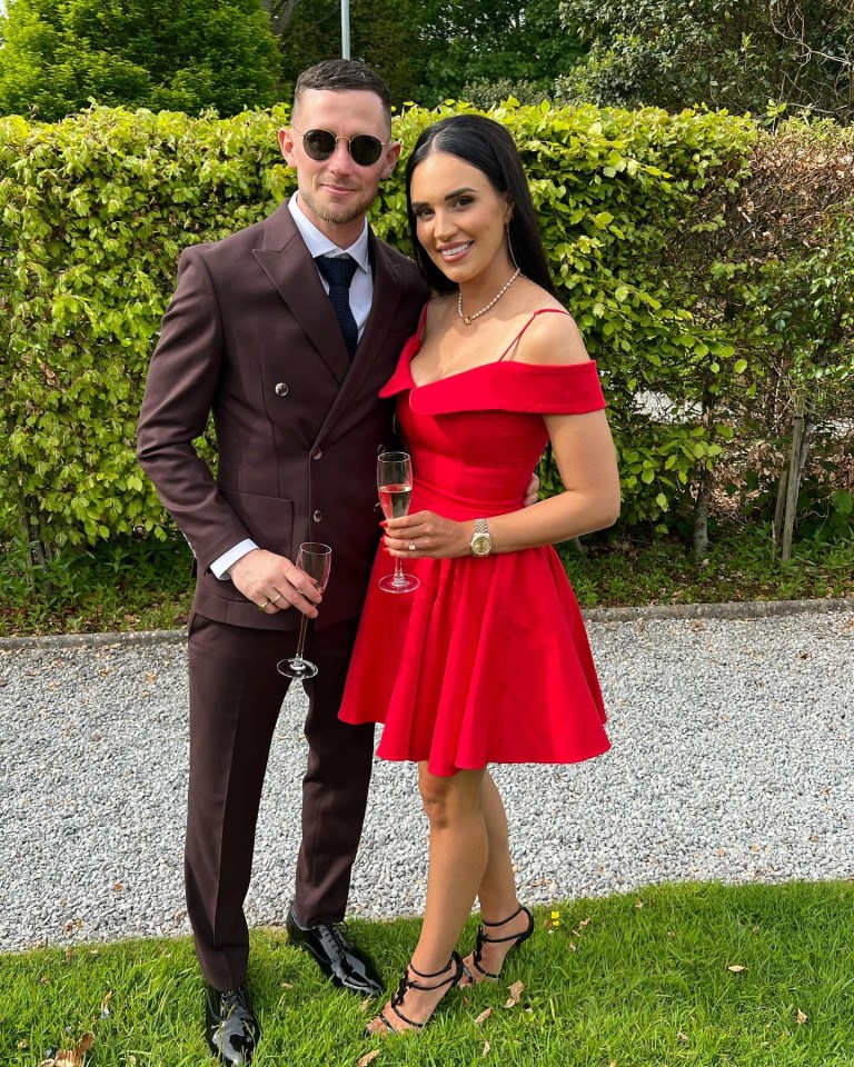 a man in a suit stands next to a woman in a red dress