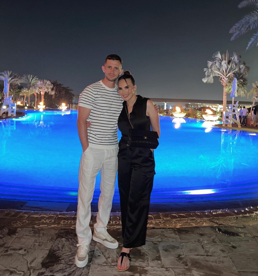 a man and a woman pose in front of a swimming pool at night