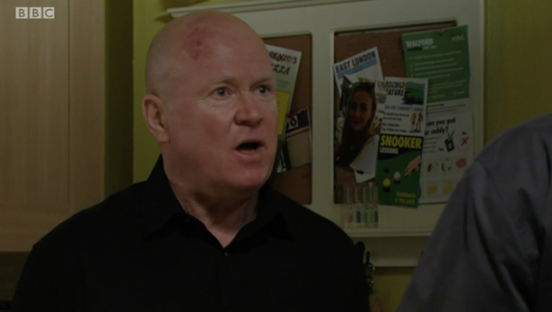 a bald man stands in front of a bulletin board that says east london