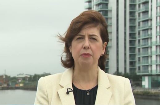 a woman in a white jacket is standing in front of a body of water .