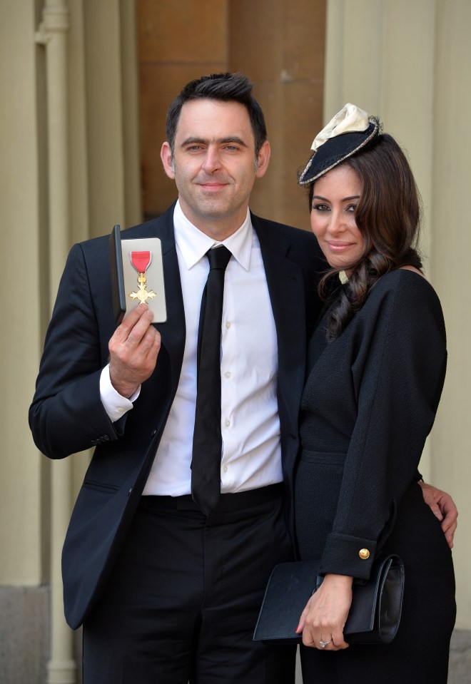 a man in a suit and tie is holding a medal