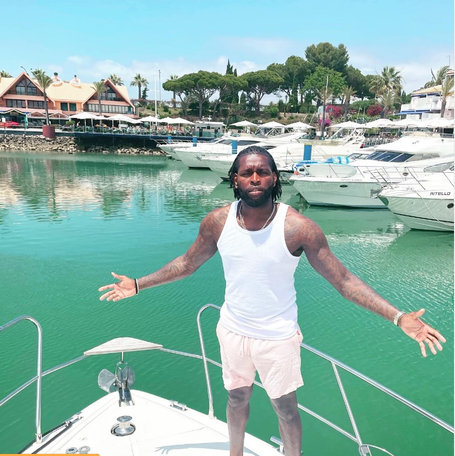 a man is standing on a boat with a yacht in the background that says mybella