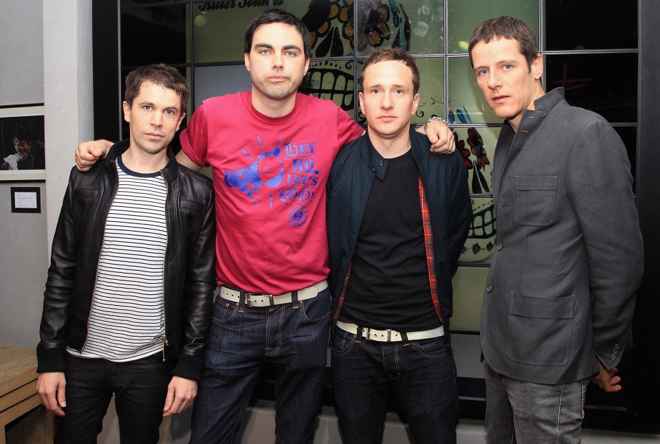 four men are posing for a picture and one of them is wearing a shirt that says ' no id ' on it