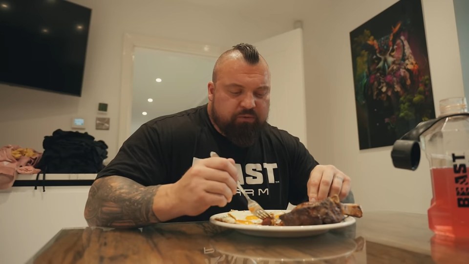 a man sitting at a table with a plate of food wearing a shirt that says fast