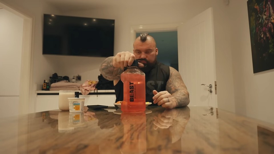 a man sitting at a table with a bottle that says beast on it