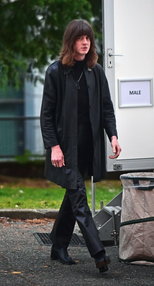 a man in a black coat walks past a sign that says male