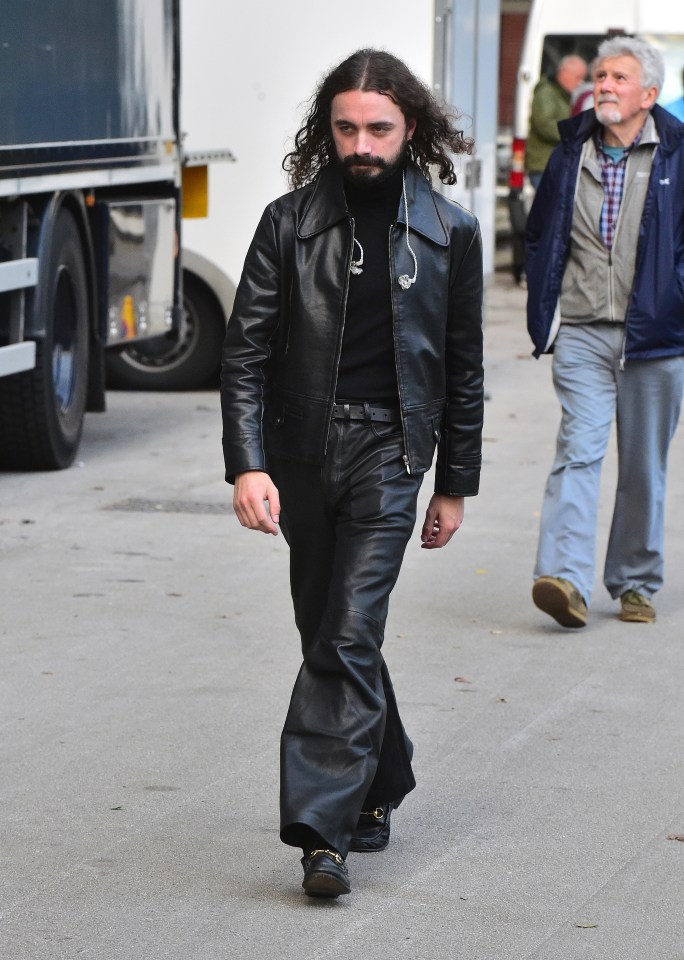 a man with long curly hair wearing a black leather jacket