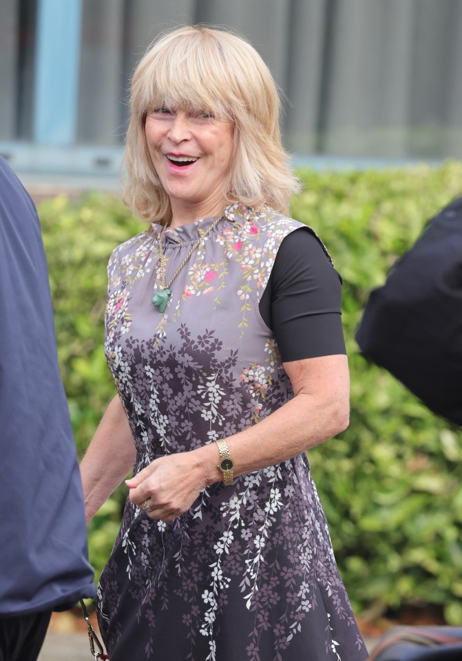 a woman wearing a floral dress and a watch smiles