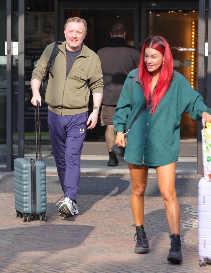 a man in a green jacket and a woman with red hair are pulling luggage