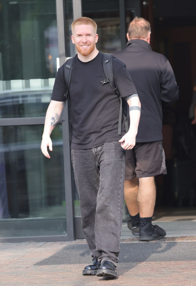 a man with a tattoo on his arm is wearing a black shirt