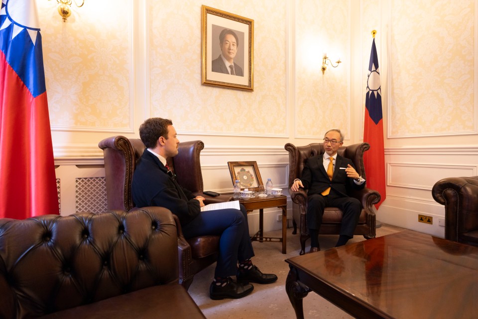 two men are sitting in a room with a picture of a man on the wall