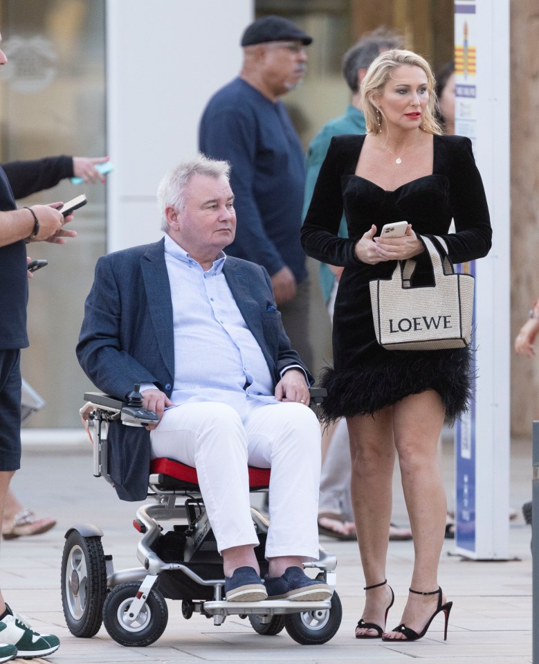 a man in a wheelchair next to a woman holding a loewe bag