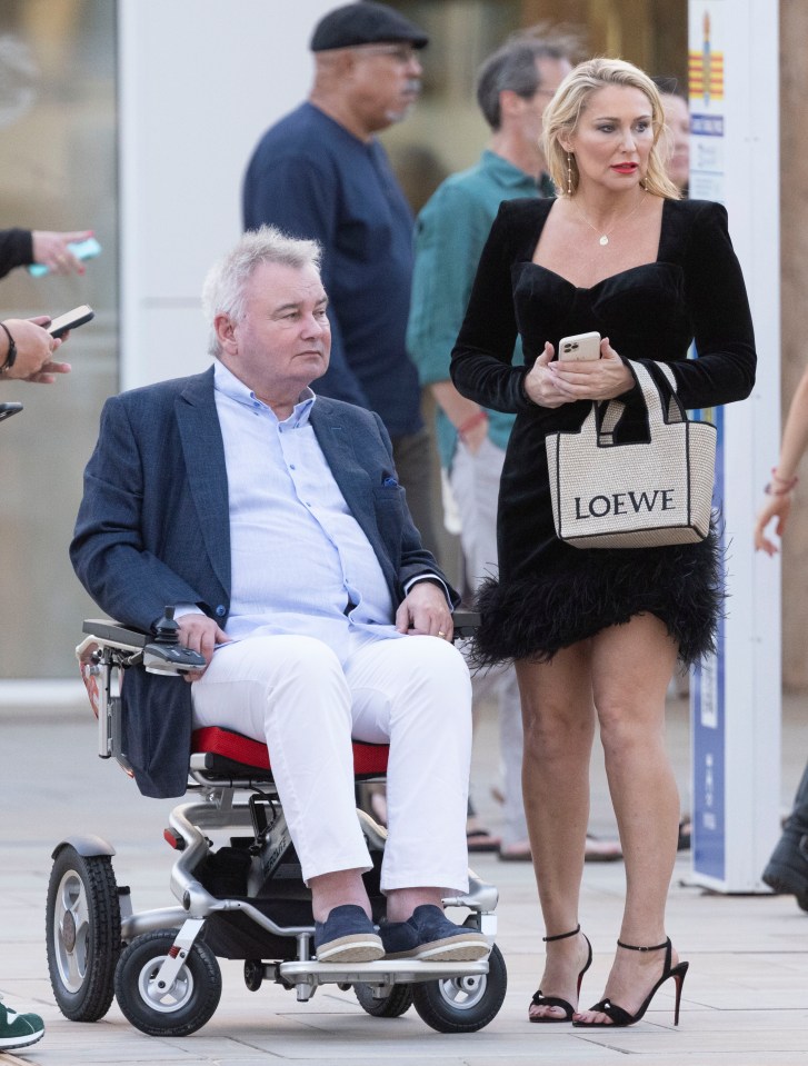 a man in a wheelchair next to a woman with a loewe bag