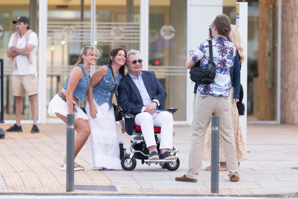 a man in a wheelchair is being photographed by two women