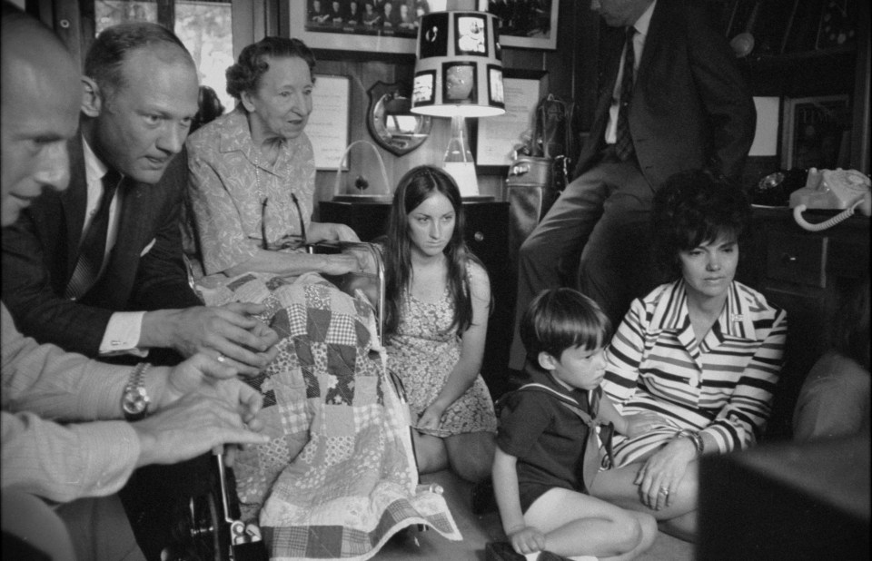 a black and white photo of a family sitting on the floor